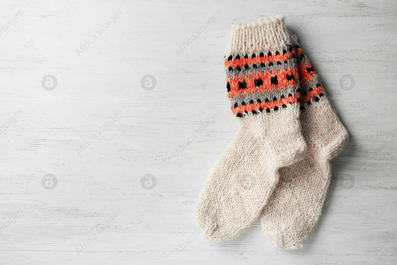Photo of Knitted socks on white wooden background, flat lay with space for text
