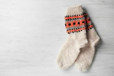 Photo of Knitted socks on white wooden background, flat lay with space for text