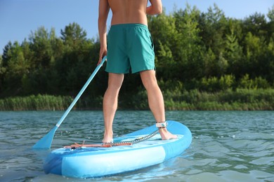 Photo of Man paddle boarding on SUP board in river, closeup