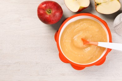 Photo of Healthy baby food. Bowl with delicious apple puree and fresh fruits on white wooden table, flat lay. Space for text