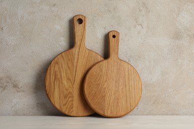 Photo of Wooden cutting boards on white table near textured wall