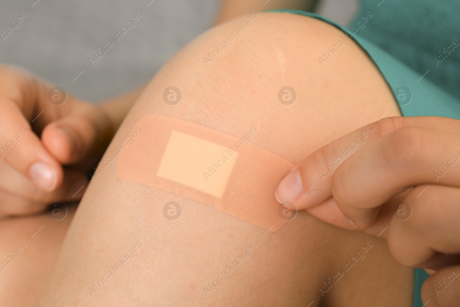Photo of Woman applying plaster on knee, closeup view