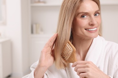 Photo of Beautiful woman brushing her hair in room