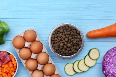 Flat lay composition with dry and natural dog food on wooden background