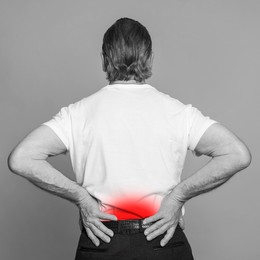 Senior man suffering from rheumatism on light background. Black and white effect with red accent in painful area