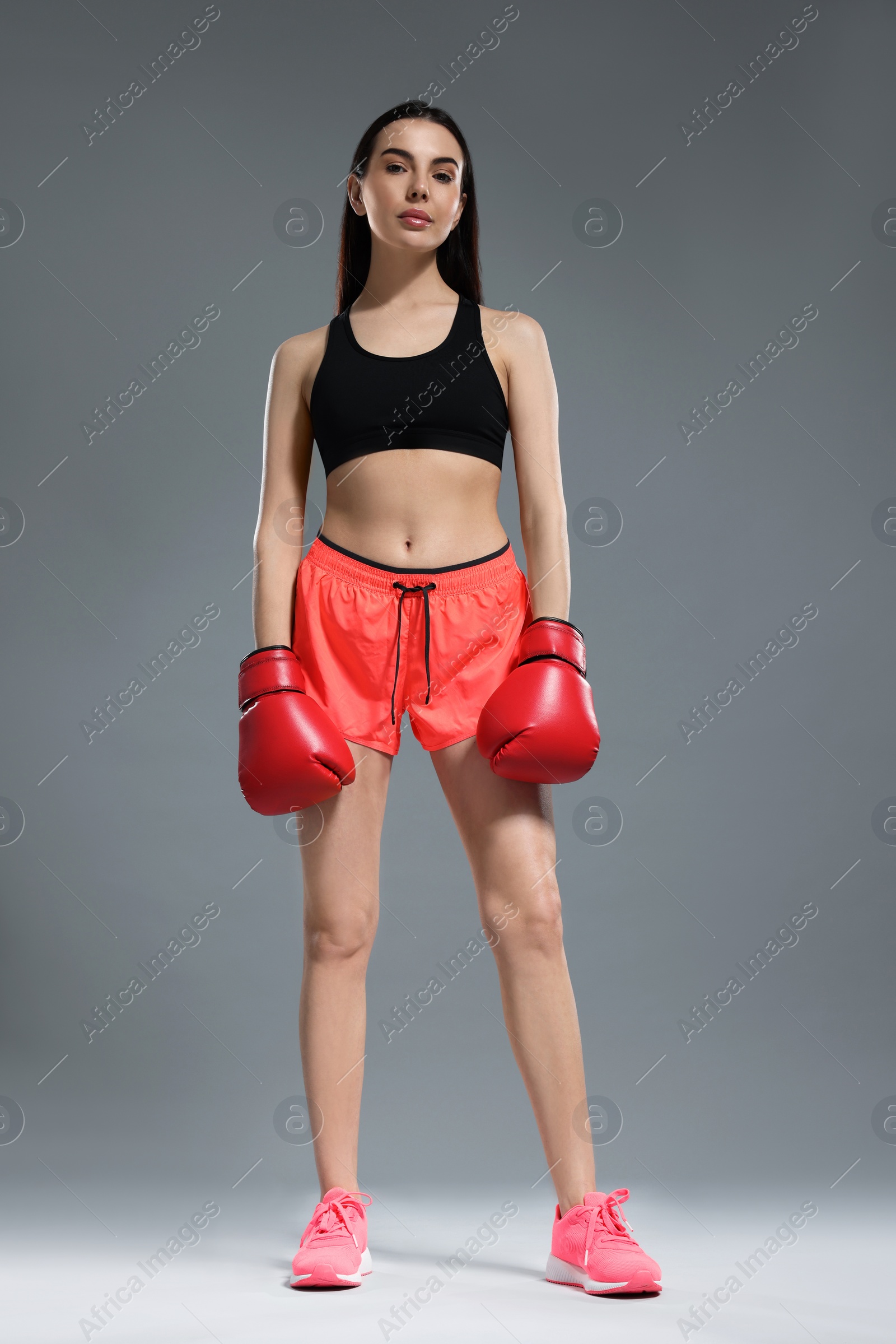 Photo of Beautiful woman in boxing gloves on grey background