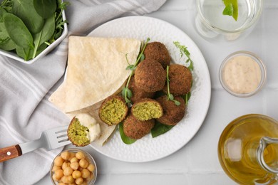 Delicious falafel balls served on white tiled table, flat lay