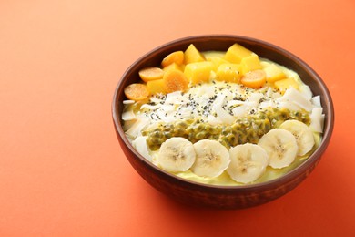 Photo of Tasty smoothie bowl with fresh fruits on orange table. Space for text