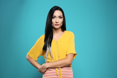 Portrait of young hippie woman with boho makeup in stylish outfit on color background