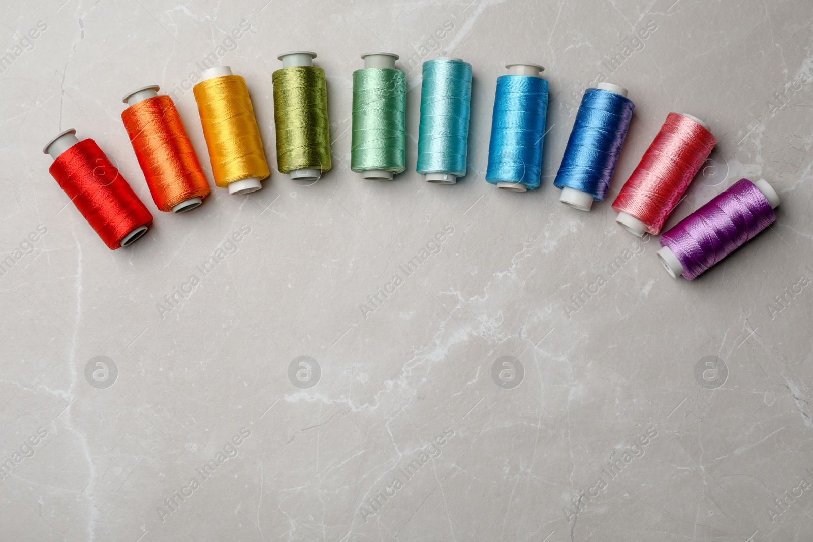 Photo of Color sewing threads on gray background, top view