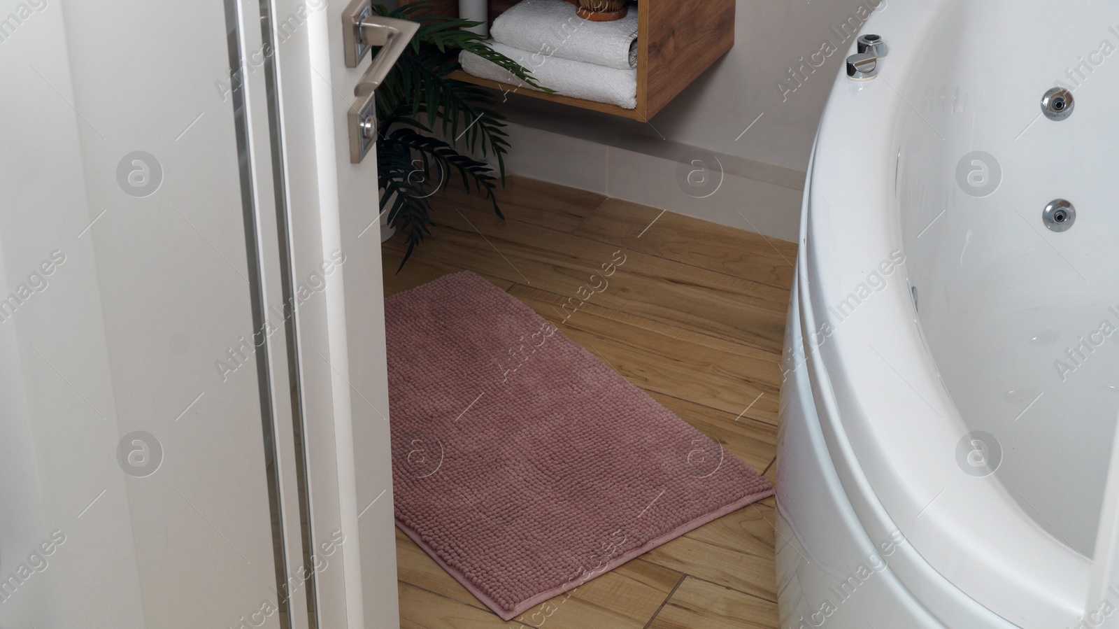 Photo of Soft bath mat on wooden floor in bathroom