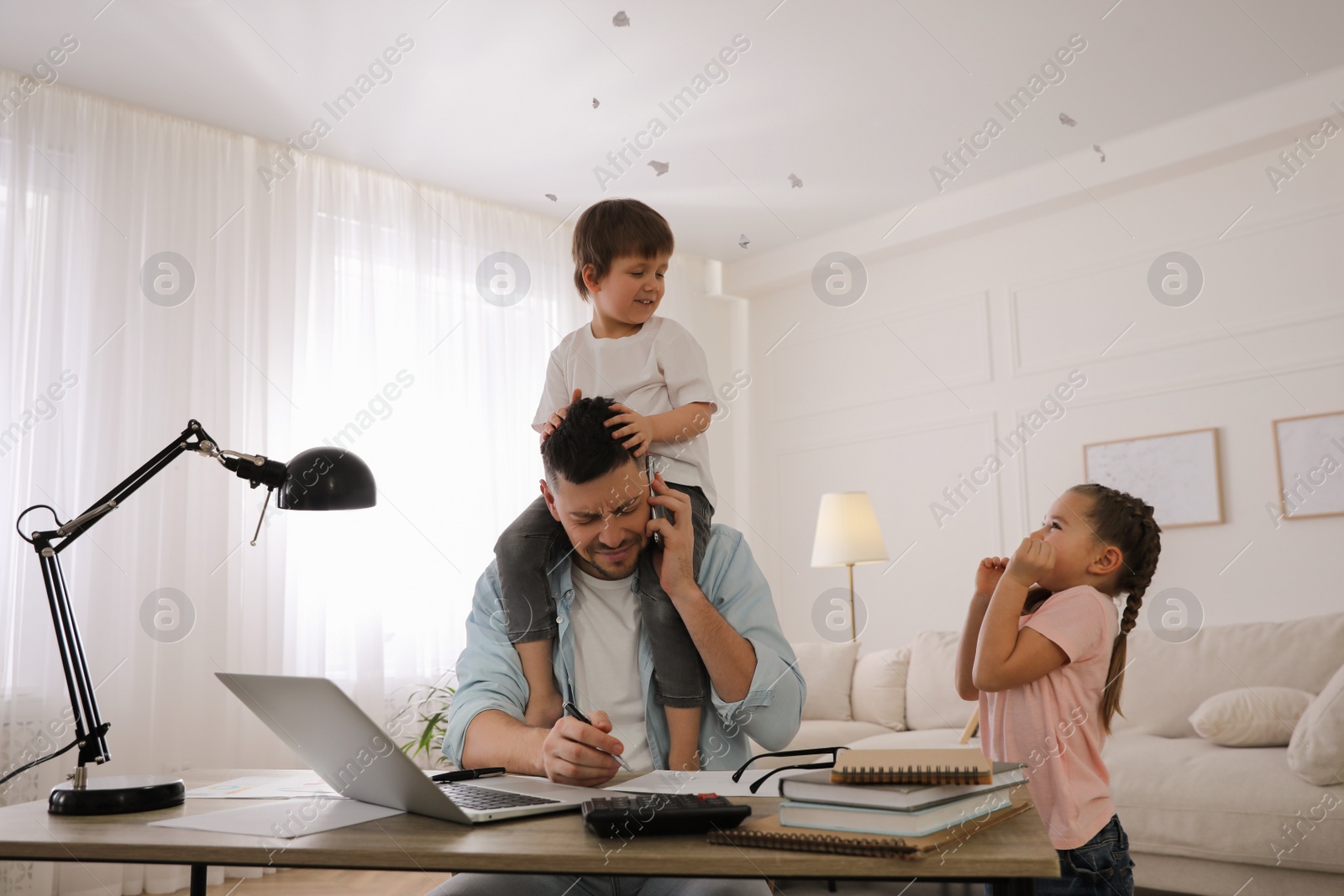 Photo of Overwhelmed man combining parenting and work at home