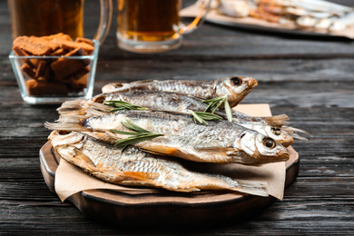 Tasty dried fish with rosemary on black wooden table