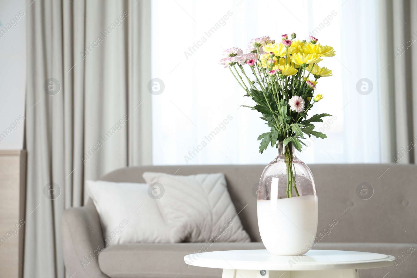 Photo of Vase with beautiful flowers on table in living room, space for text. Stylish element of interior design