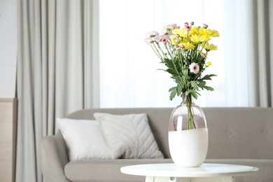 Photo of Vase with beautiful flowers on table in living room, space for text. Stylish element of interior design