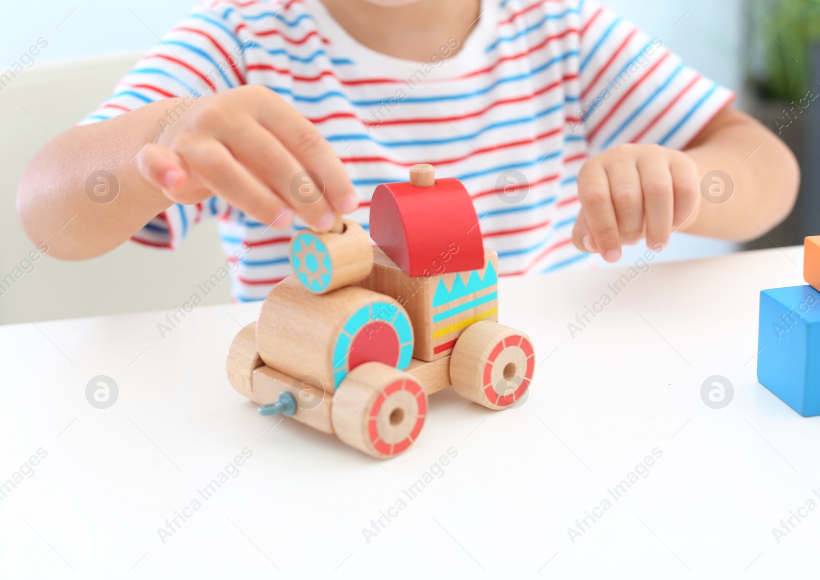 Photo of Little boy playing with toy at white table, closeup