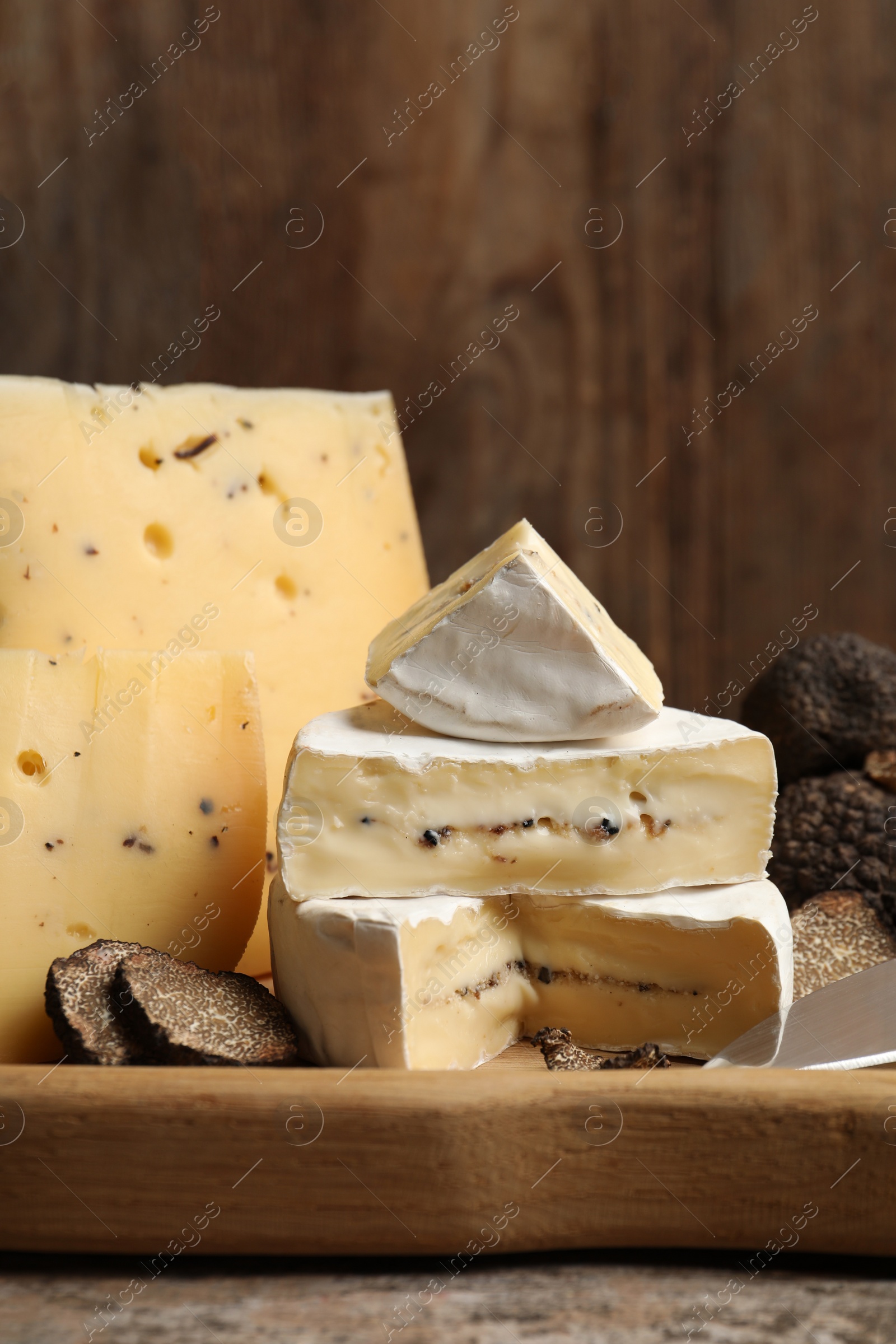 Photo of Different types of cheese and truffles on wooden board