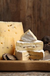 Photo of Different types of cheese and truffles on wooden board