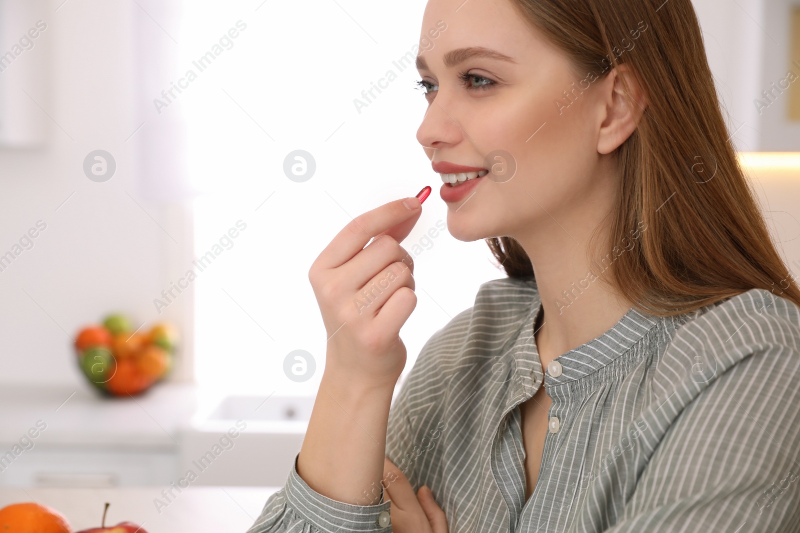 Photo of Young woman taking vitamin capsule on blurred background. Space for text
