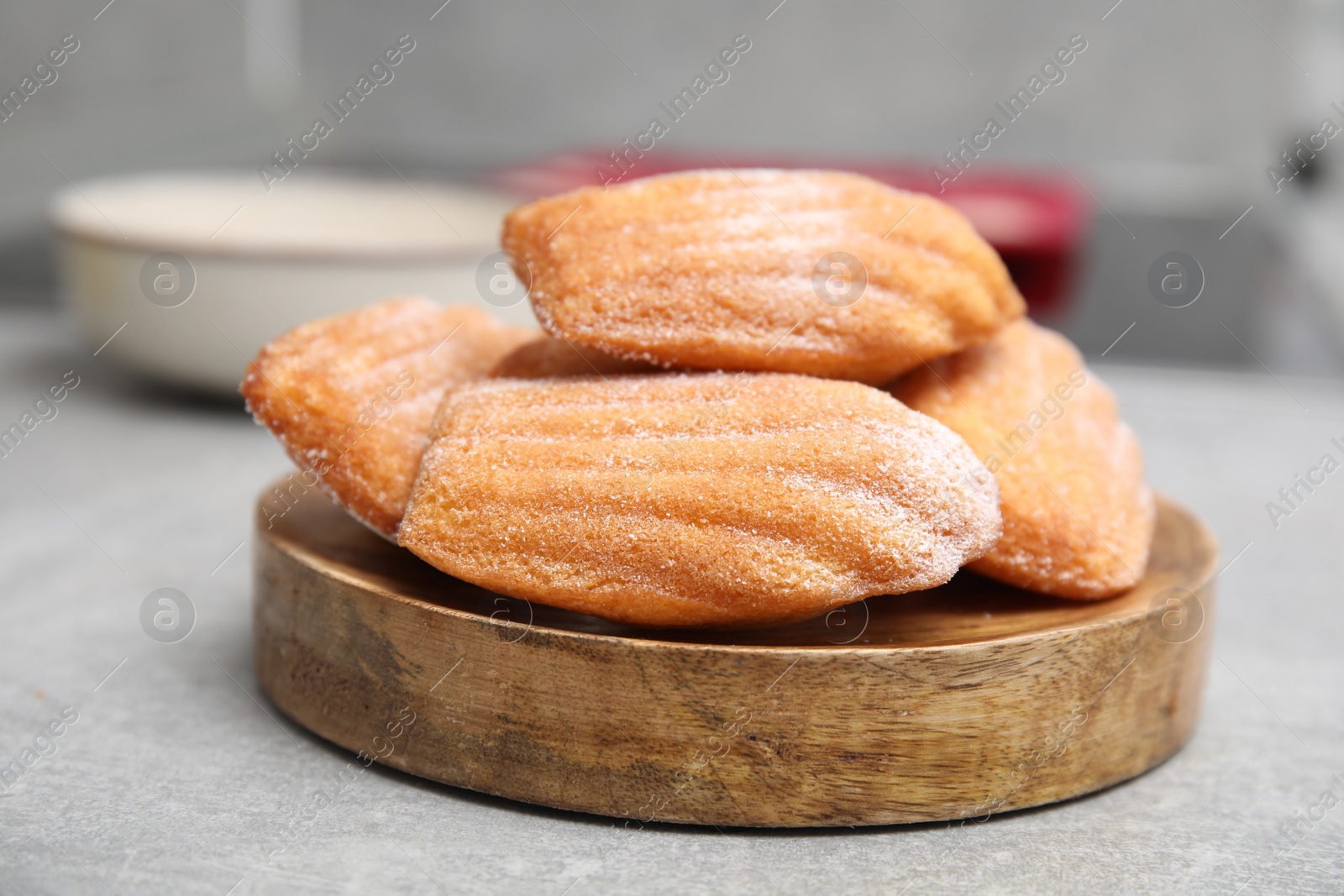 Photo of Wooden board with madeleine cookies on grey table, closeup