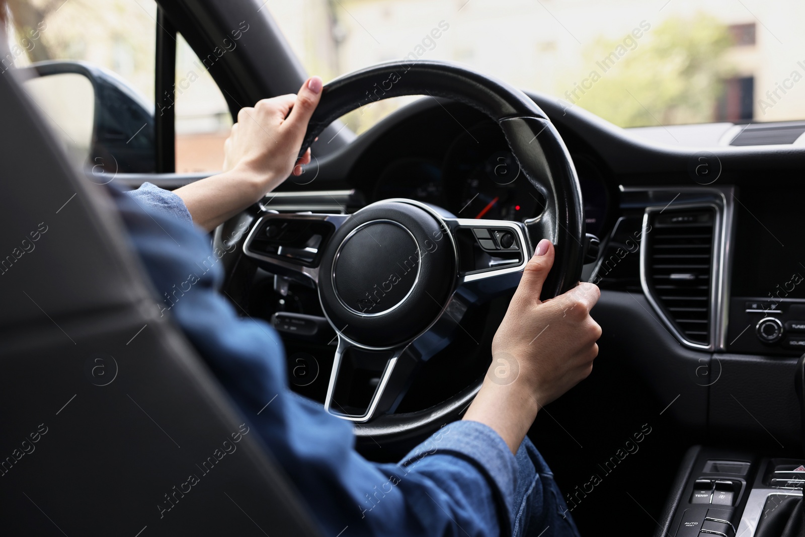 Photo of Woman holding steering wheel while driving her car, closeup