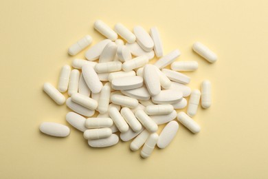 Vitamin pills on pale yellow background, flat lay