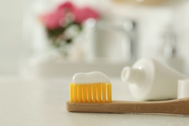 Photo of Brush with toothpaste on bathroom counter, closeup. Space for text