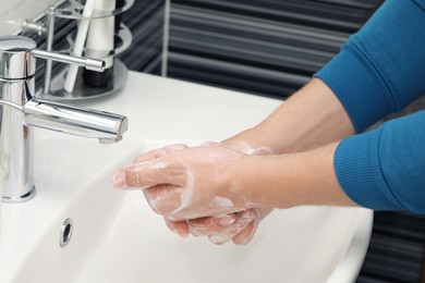 Photo of Man washing hands with soap over sink in bathroom, closeup