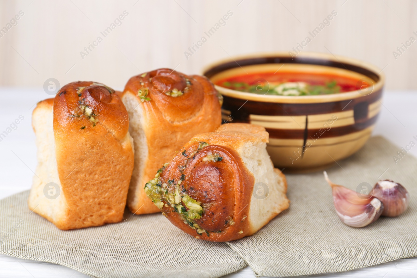 Photo of Delicious pampushky (buns with garlic) served for borsch on white table, closeup. Traditional Ukrainian cuisine