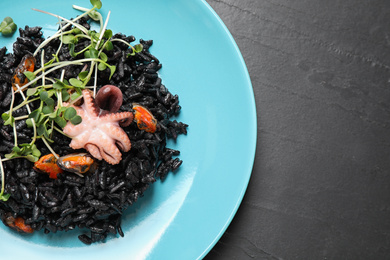 Photo of Delicious black risotto with seafood on grey table, top view