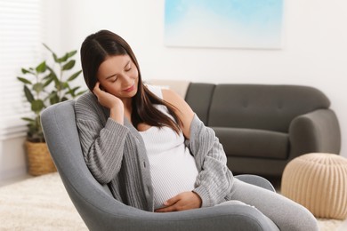 Photo of Beautiful pregnant woman napping in armchair at home