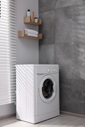 Laundry room interior with washing machine near grey wall