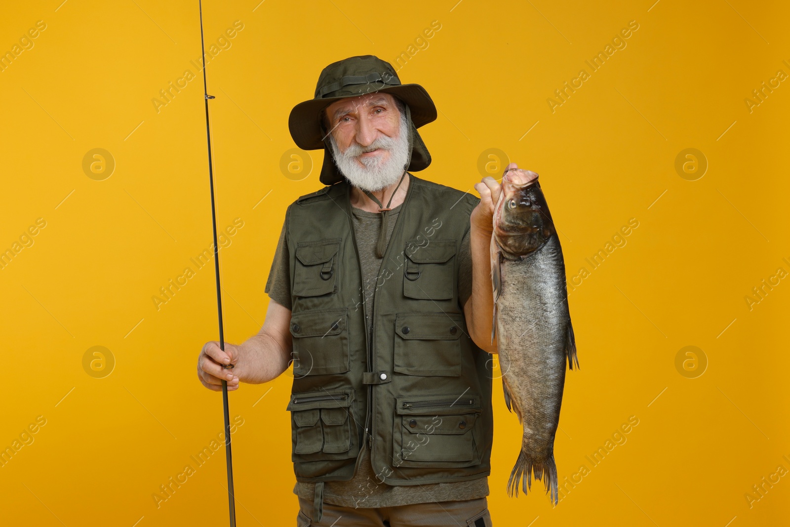 Photo of Fisherman with rod and catch on yellow background