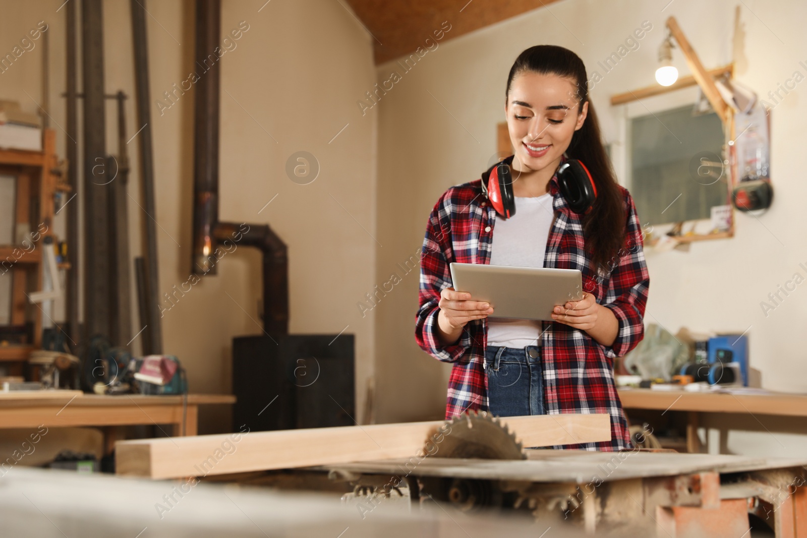 Photo of Professional carpenter with tablet near sawmill machine in workshop