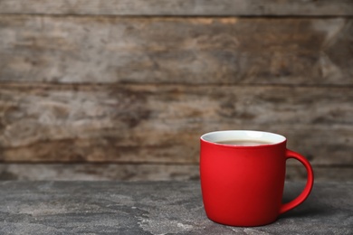 Red ceramic cup with hot aromatic coffee on table