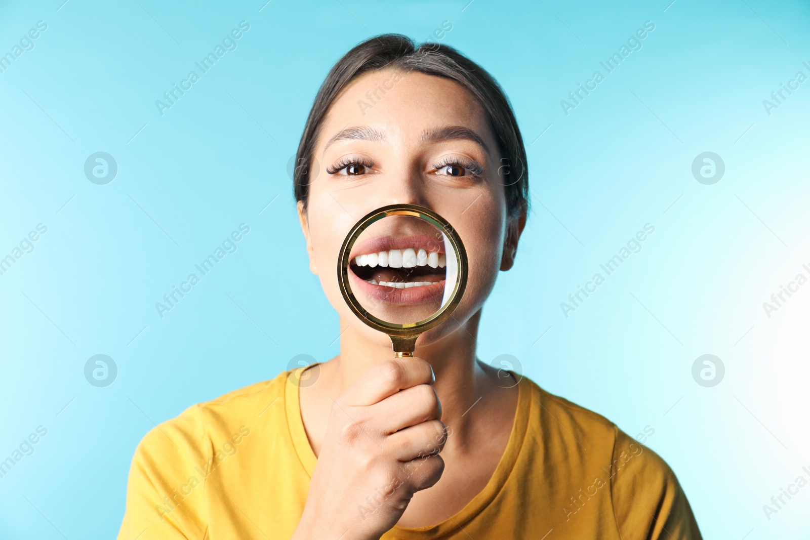 Photo of Young woman with healthy teeth and magnifier on color background