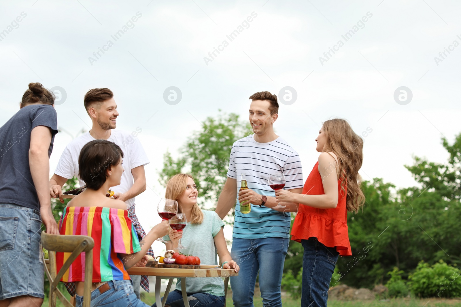Photo of Young people having barbecue at table outdoors
