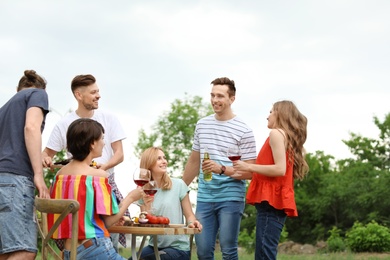 Photo of Young people having barbecue at table outdoors