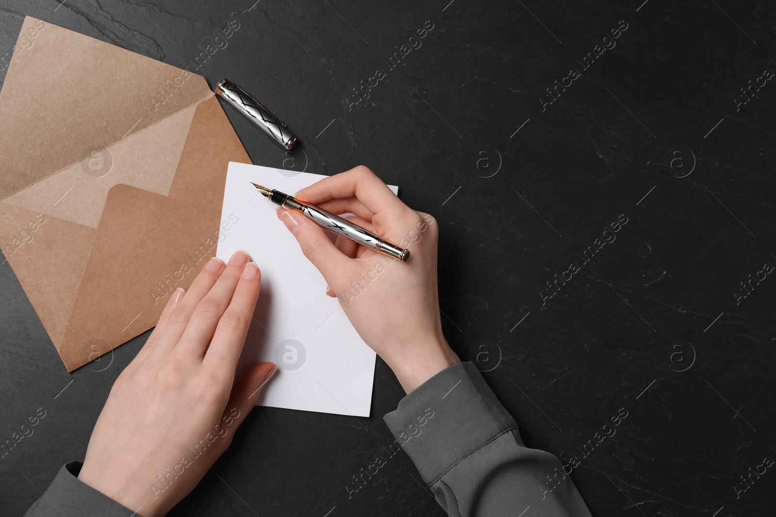 Photo of Woman writing letter at black textured table, top view. Space for text