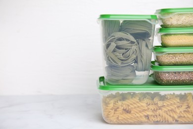 Plastic containers filled with food products on white table. Space for text