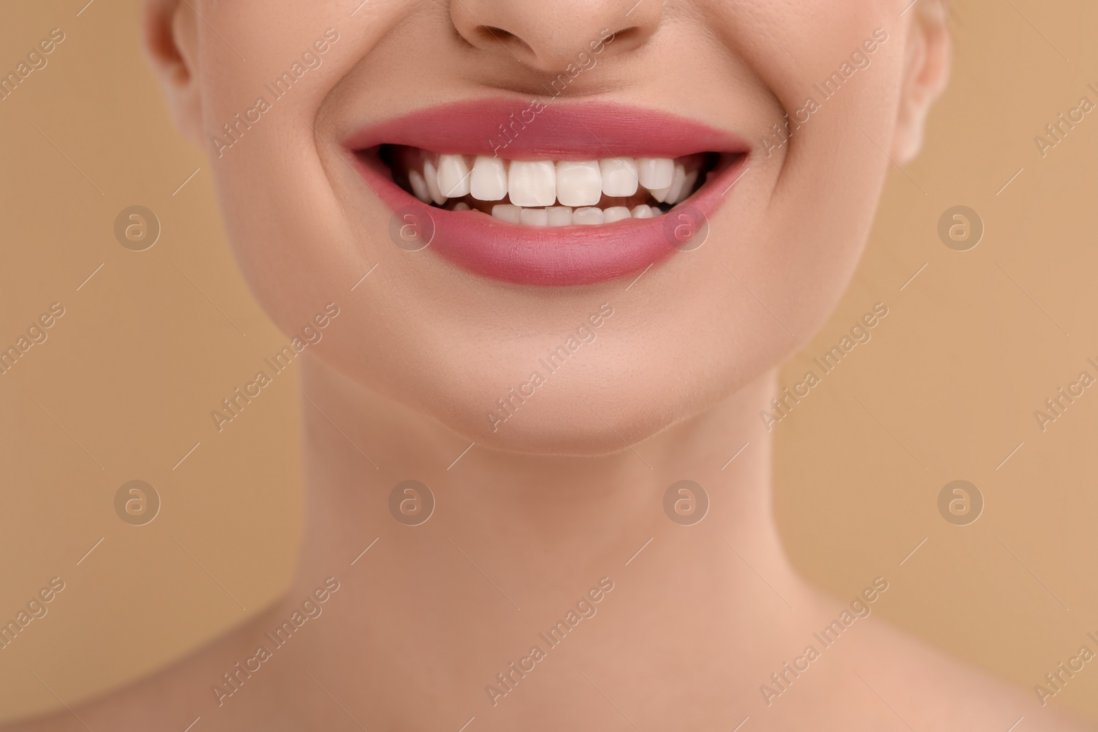 Photo of Young woman with beautiful smile on beige background, closeup