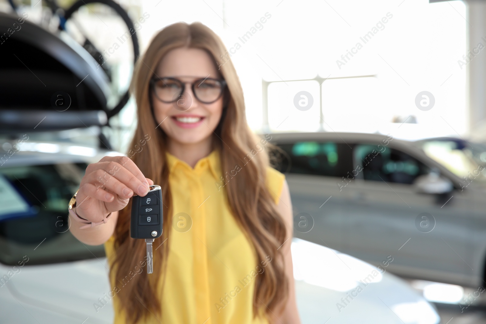 Photo of Young saleswoman with car key at workplace