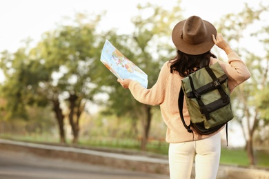 Traveler with map and backpack on city street, back view