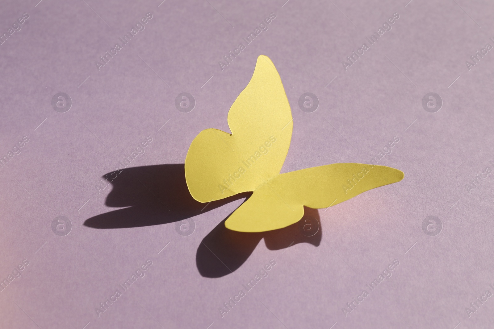 Photo of Yellow decorative paper butterfly on violet background