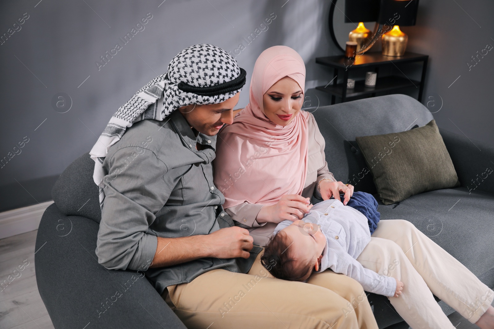 Photo of Happy Muslim family with little son in living room