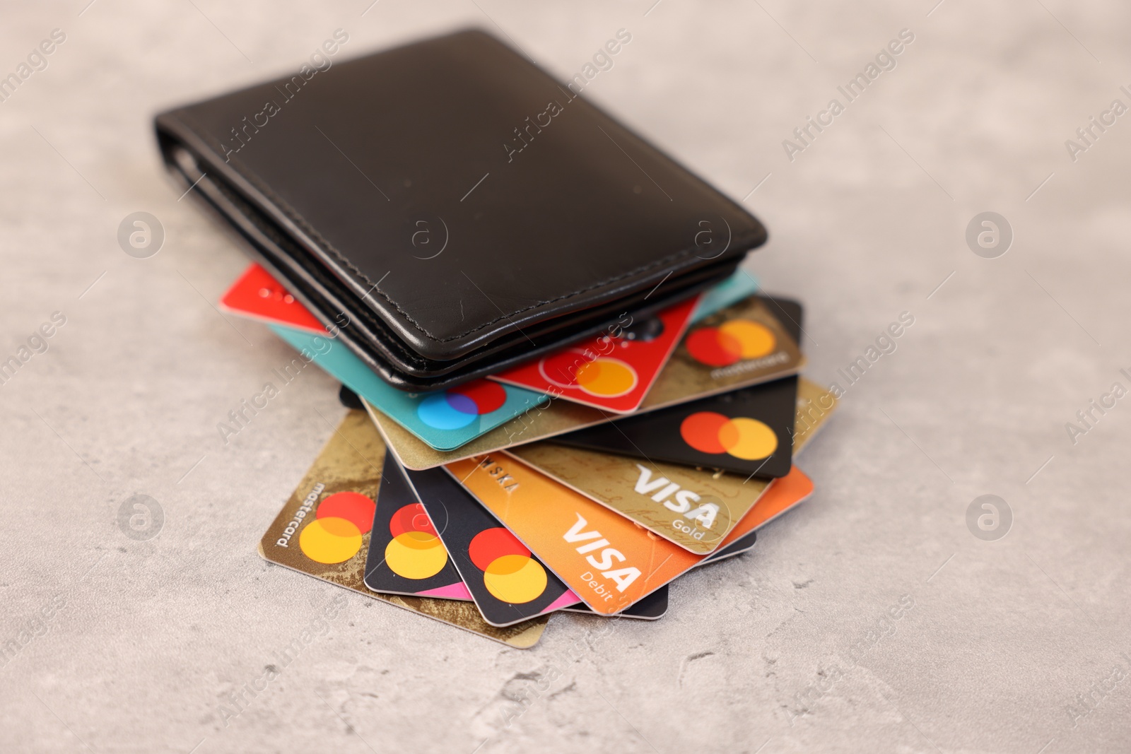 Photo of LEIDEN, NETHERLANDS - MARCH 07, 2024: Bank cards of Visa and Mastercard payment systems in leather wallet on light grey table