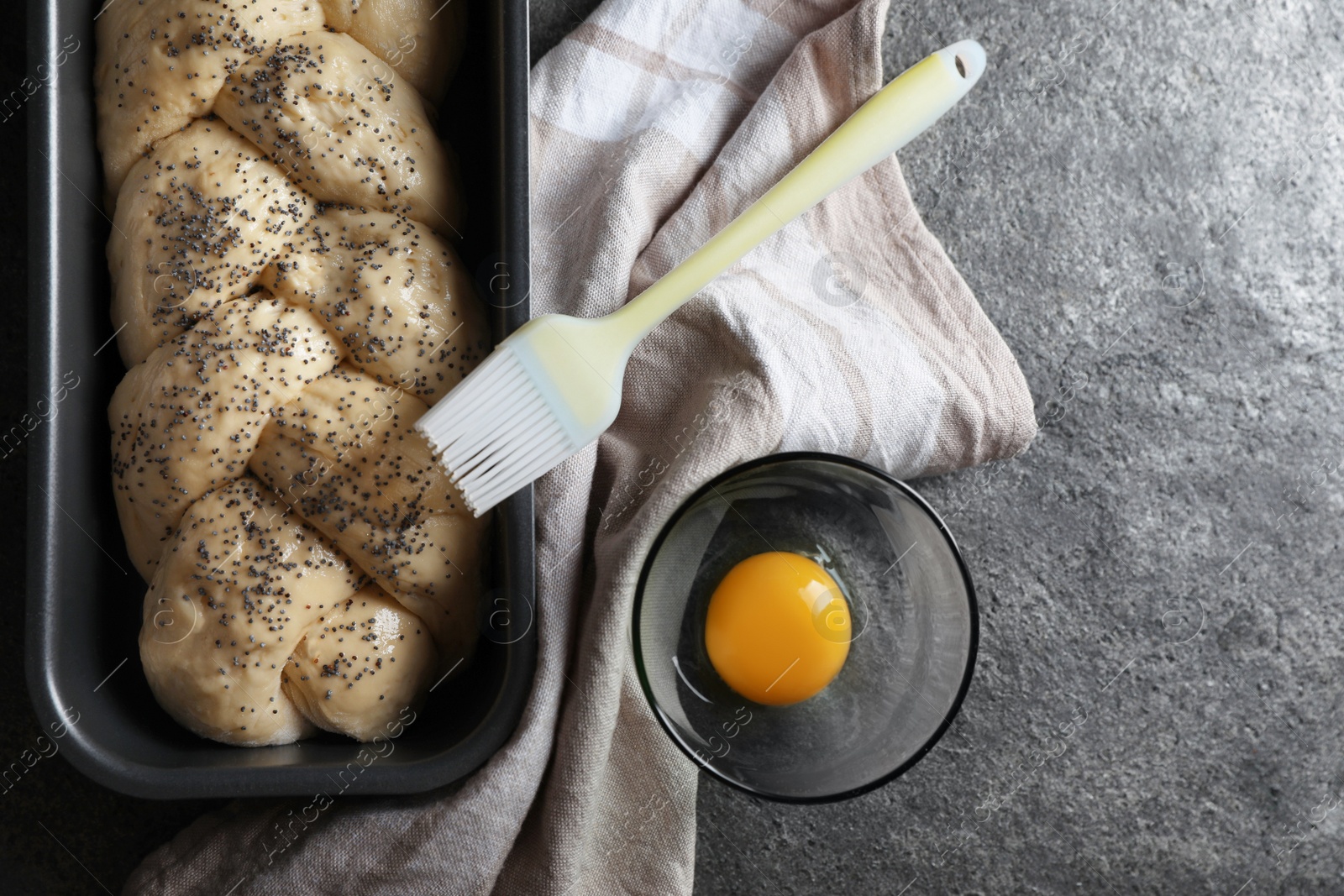 Photo of Homemade braided bread and ingredients on grey table, flat lay with space for text. Cooking traditional Shabbat challah