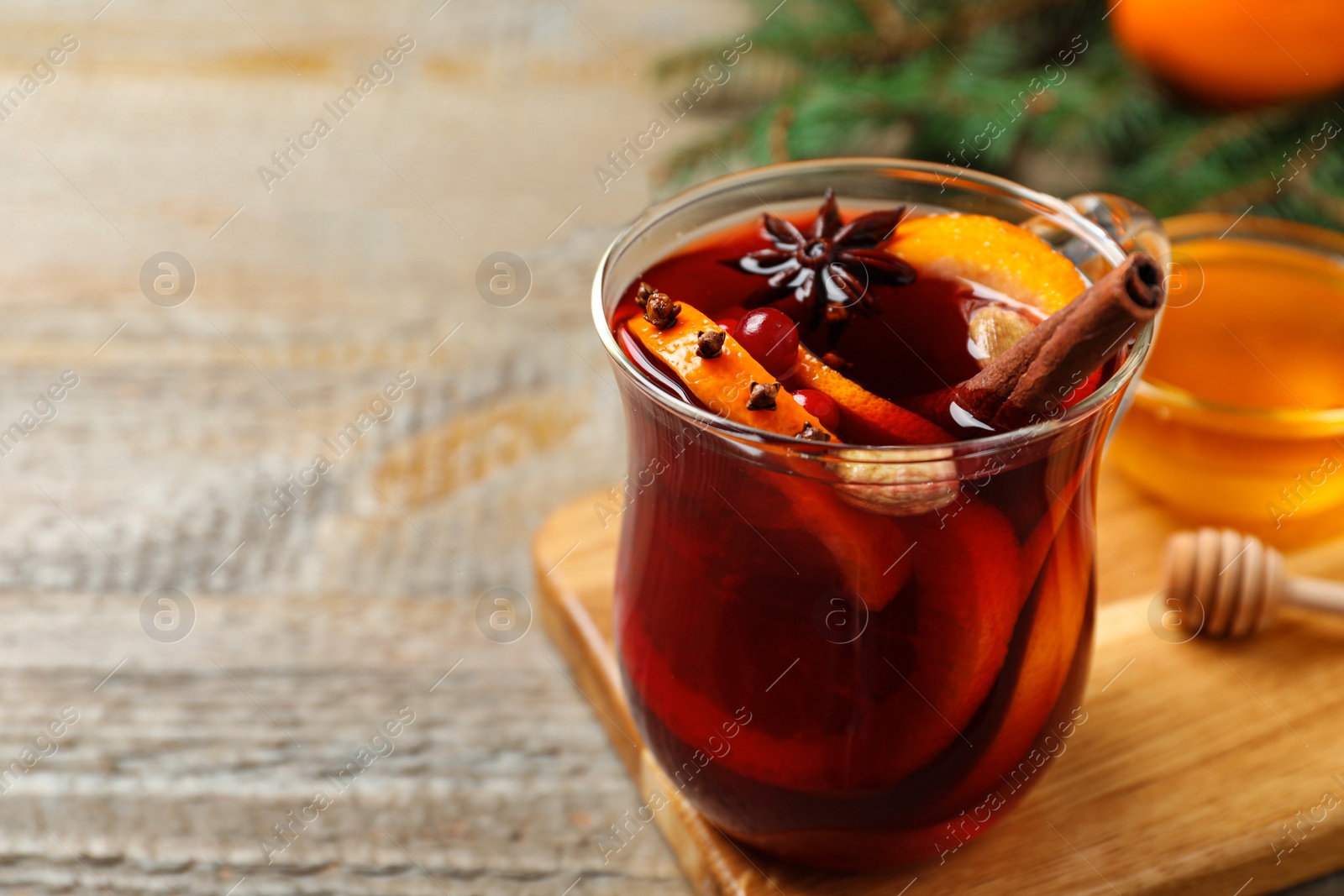 Photo of Glass cup of tasty mulled wine on wooden table. Space for text