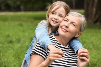 Photo of Happy grandmother with her granddaughter spending time together in park, space for text