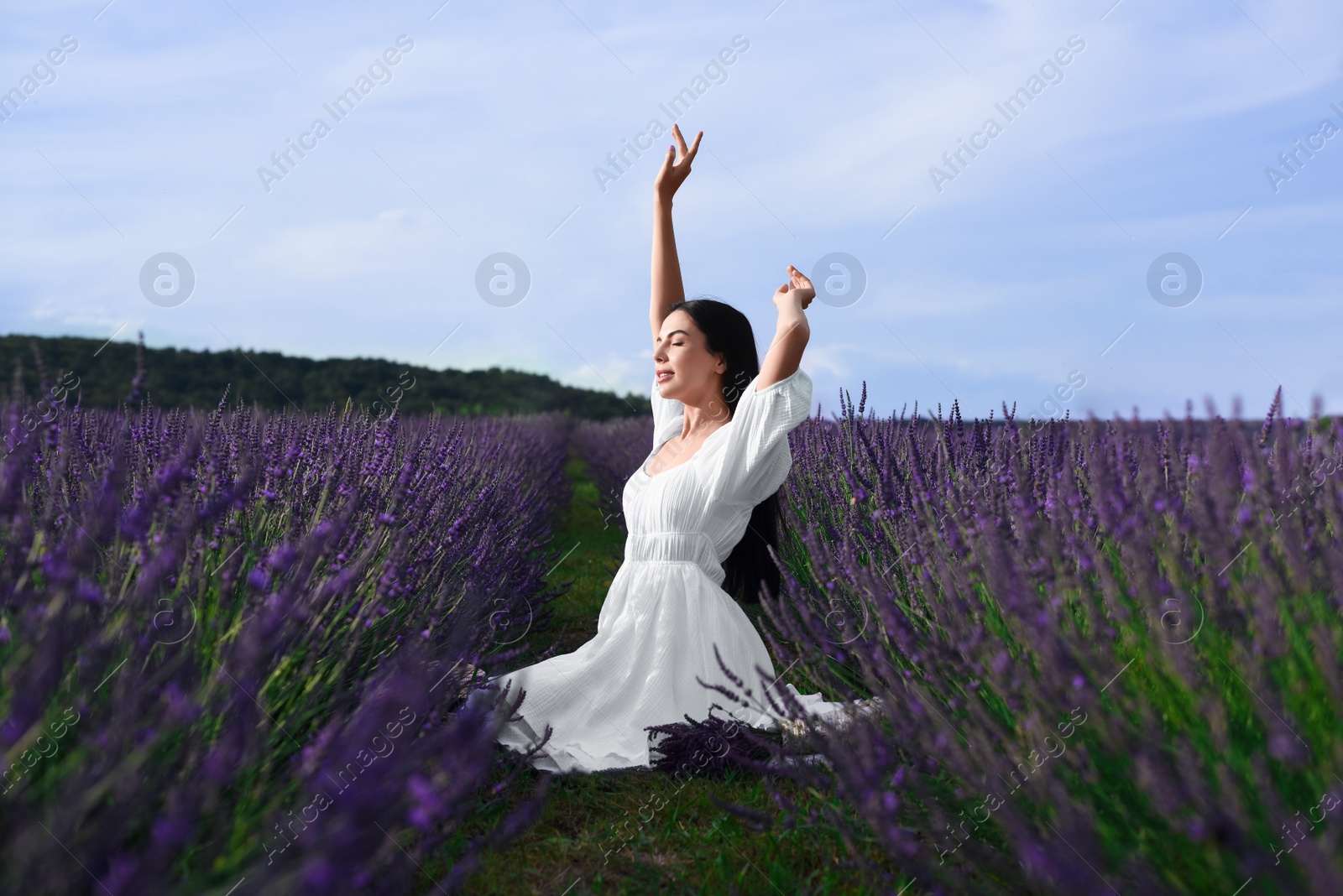 Photo of Beautiful young woman sitting in lavender field